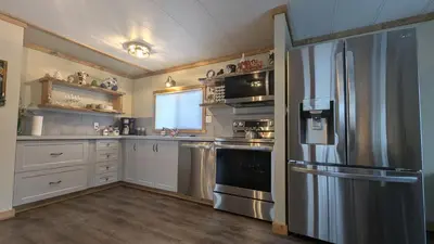 a kitchen with a stainless steel refrigerator and white cabinets at Hillcrest Hideaway: Spacious Mountain View Oasis in Hillcrest Mines