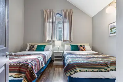 two beds in a small room with a window at Relaxing Mountain Getaway at Mystic Springs in Canmore