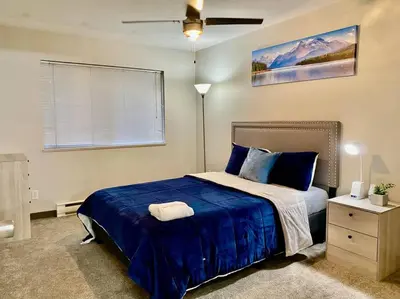 a bedroom with a bed with blue sheets and a ceiling fan at All private 2 BRoom w 2 QUEEN BEDS-1 BTHRM-FREE PARKING-FAST WI-FI-CENTRAL LOCATION in Grande Prairie