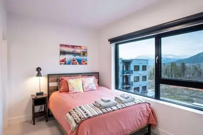 a bedroom with a bed and a large window at Alpine Retreat by Revelstoke Vacations in Revelstoke