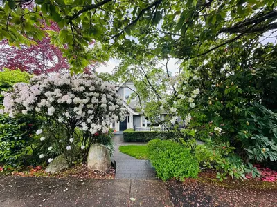 a house with a flowering tree and a walkway at Cozy Home in Dunbar in Vancouver