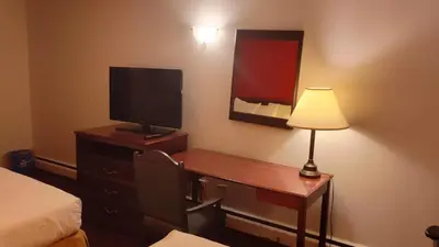 a hotel room with a desk with a television and a lamp at Metro Inn in Calgary