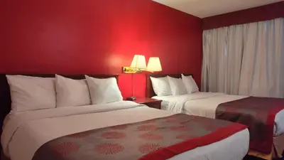 two beds in a hotel room with red walls at Metro Inn in Calgary