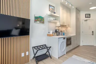 a kitchen with a washing machine and a chair in it at Newly Renovated KING BED STUDIO in the Village in Whistler