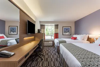 a hotel room with two beds and a desk at Microtel Inn & Suites by Wyndham Fort Saint John in Fort Saint John