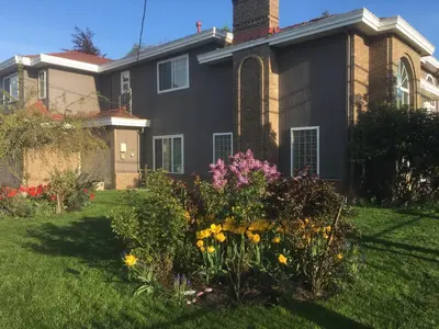 a house with a garden of flowers in the yard at Rose Garden Vancouver Airport - Richmond BC in Richmond