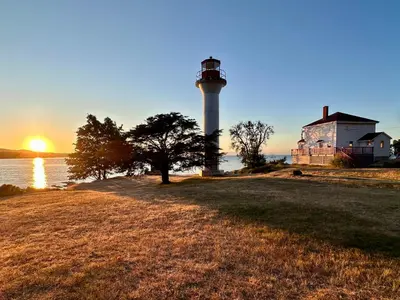 a lighthouse on the shore of a body of water at The Grove B&B Mayne Island in Mayne Island