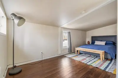 a bedroom with a bed and a lamp on a wooden floor at Dinos Last Post - Family Friendly 4 Bedrooms in Drumheller
