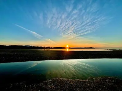 a sunset over a body of water with the sun at Beachside Townhouses at The Pacific Shores Strata Property in Nanoose Bay