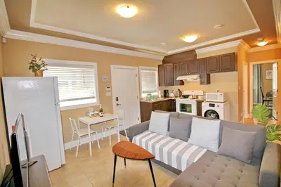 a living room with a couch and a kitchen at Close to YVR King Sized Private Entrance Suite in Richmond