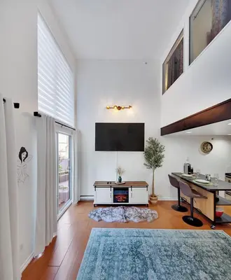 a white living room with a desk and a television at Stylish Two-Story Loft with Rooftop Deck in Vancouver