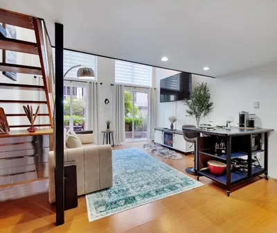 a living room with a staircase and a couch and a table at Stylish Two-Story Loft with Rooftop Deck in Vancouver