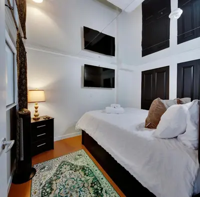 a bedroom with a bed with white sheets and a rug at Stylish Two-Story Loft with Rooftop Deck in Vancouver