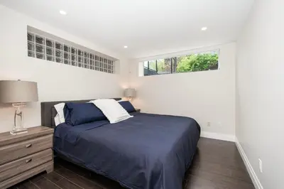 a bedroom with a blue bed and two windows at Elegant and Roomy Forest Getaway in North Vancouver