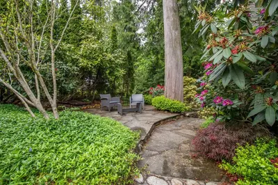 a garden with two chairs and flowers and trees at Elegant and Roomy Forest Getaway in North Vancouver