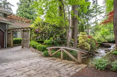 a wooden bench sitting on a walkway in a garden at Elegant and Roomy Forest Getaway in North Vancouver