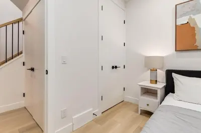 a bedroom with white walls and a bed and a lamp at Perfect for Long Stays Free Parking Pets Allowed in Calgary