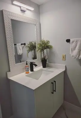 a bathroom with a white sink and a mirror at A new luxury basement apartment in Surrey