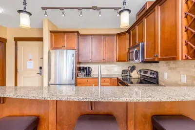 a kitchen with wooden cabinets and a granite counter top at Stonegate Resort Unit C105 in Kelowna