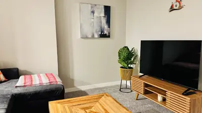 a living room with a flat screen tv on a wooden stand at Tee's Oasis in Calgary