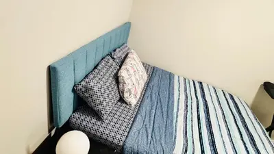 a bed with a blue head board with pillows at Tee's Oasis in Calgary
