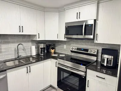 a kitchen with white cabinets and a sink and a microwave at Tee's Oasis in Calgary
