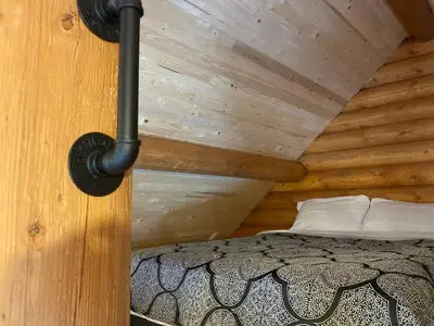 a bedroom with a bed in a wooden cabin at Lofted log cabin with fire table in Kelowna