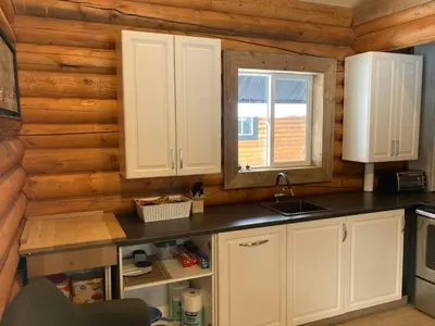 a kitchen with white cabinets and a window in a log cabin at Lofted log cabin with fire table in Kelowna