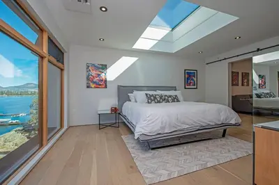 a bedroom with a bed and a large window at Nest Luxury Modern Lake House in Penticton