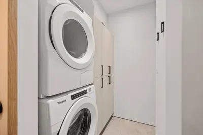 a washer and dryer in a white laundry room at Nest Luxury Modern Lake House in Penticton