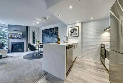 a kitchen with a counter and a living room at Ski-In-Out, Pool, Hot Tub, Sauna in Whistler