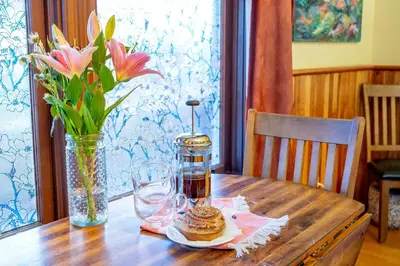 a wooden table with a vase of flowers and a vase of flowers at Victoria Falls House Inn in Nelson