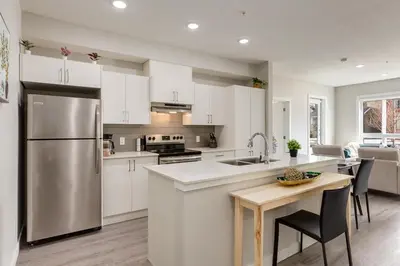 a kitchen with white cabinets and a stainless steel refrigerator at Free Parking, Close to Downtown, Pet Friendly in Calgary