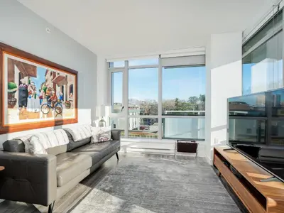 a living room with a couch and a flat screen tv at Escher Escape - Art-filled retreat with work desk by Victoria Prime! in Victoria