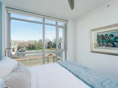 a bedroom with a bed and a large window at Escher Escape - Art-filled retreat with work desk by Victoria Prime! in Victoria
