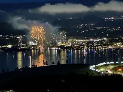 a fireworks display over the water with a city at night at Lake and the City Bed and Breakfast in West Kelowna