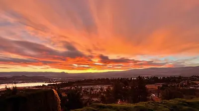 a sunset view of a city and a river at Lake and the City Bed and Breakfast in West Kelowna