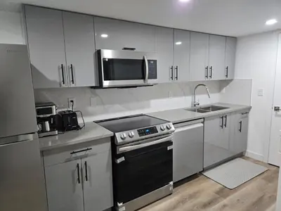 a kitchen with white cabinets and a stove and a microwave at Staycation3179 in Edmonton