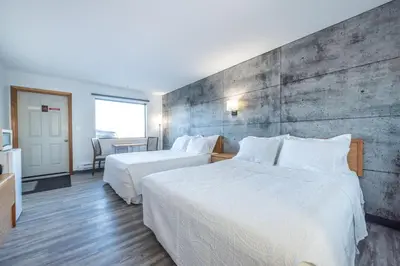 a hotel room with two beds and a concrete wall at Blue Horse Motel in Beiseker