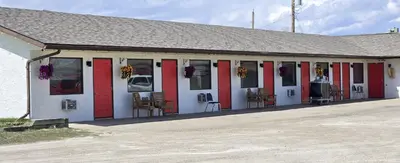 a building with red and white doors and chairs at Blue Horse Motel in Beiseker