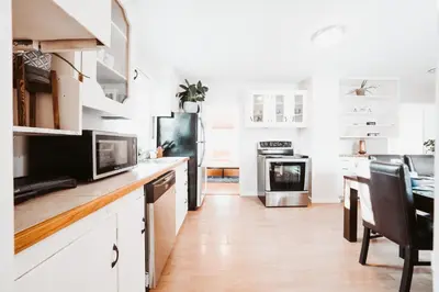 a kitchen with white cabinets and a black refrigerator at Stay & Play - Central Family Friendly in Calgary
