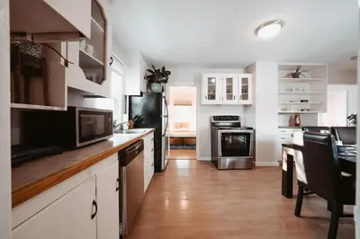 a kitchen with white cabinets and a black refrigerator at Stay & Play - Central Family Friendly in Calgary