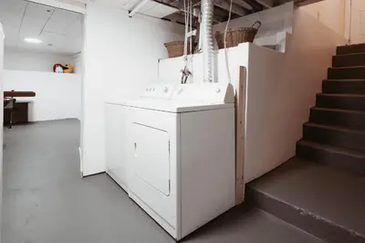 a white kitchen with a sink and a staircase at Stay & Play - Central Family Friendly in Calgary