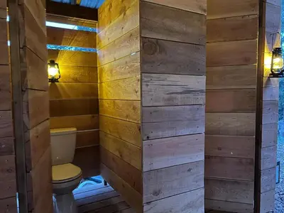 a bathroom with a toilet and wooden walls at Butterfly Cottage - Glamping in Oliver