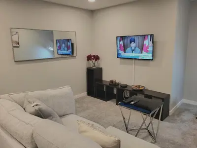 a living room with a couch and a tv on the wall at Home away from Home in Calgary