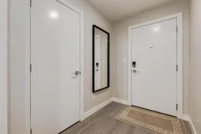 a hallway with a white door and a mirror at Inner City Apartment, Pet Friendly, Free Underground Parking in Calgary