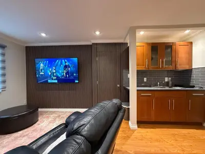 a living room with a leather couch and a flat screen tv at Place near the Coquitlam River Park in Coquitlam