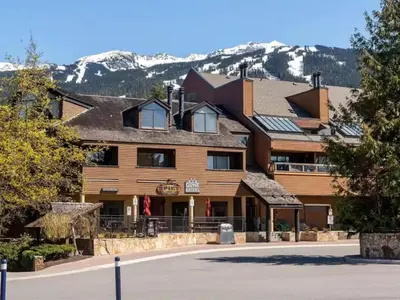 a large wooden building with mountains in the background at Large Village loft with Private Hot Tub and Private Sauna in Whistler