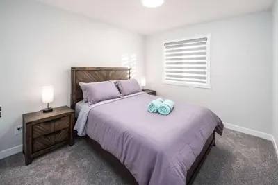 a bedroom with a large bed and a night stand at Near Downtown, Large 3BR! FREE Banff Pass, Netflix, Parking! in Calgary