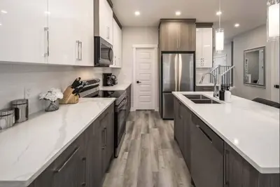 a large kitchen with white counter tops and wooden cabinets at Near Downtown, Large 3BR! FREE Banff Pass, Netflix, Parking! in Calgary